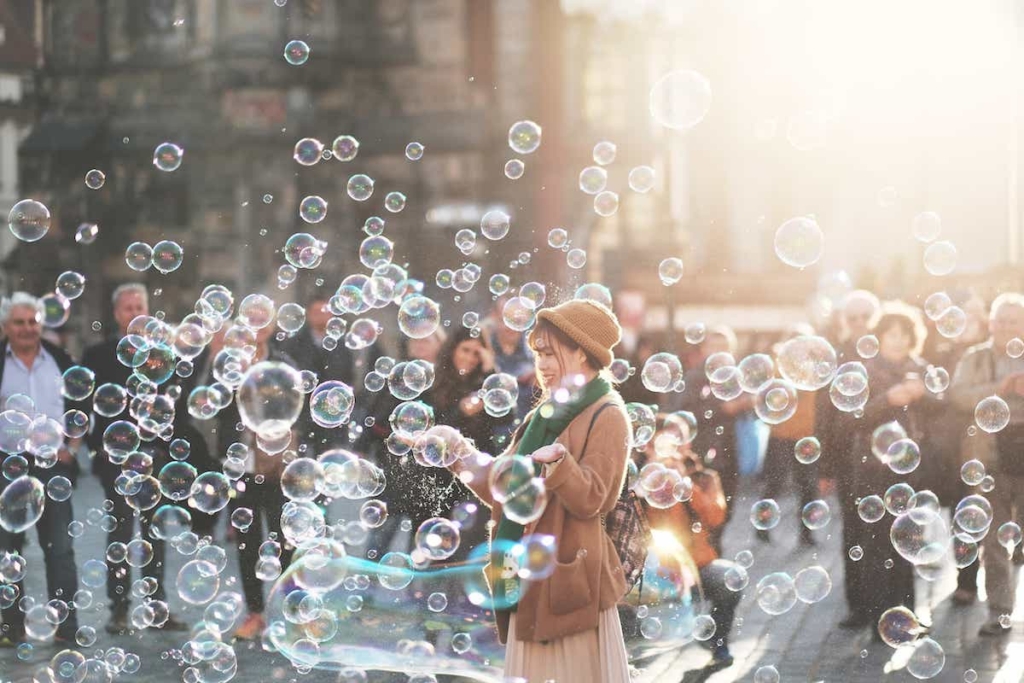A woman with arms out standing in the middle of a bunch of bubbles
