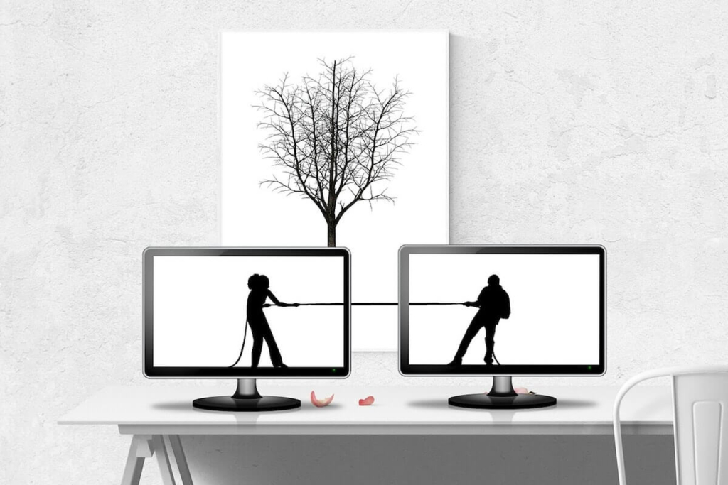 Two computer screens close together. One has a silhouette of a woman pulling on one end of a rope and the other has a silhouette of a man pulling on the other end of a rope